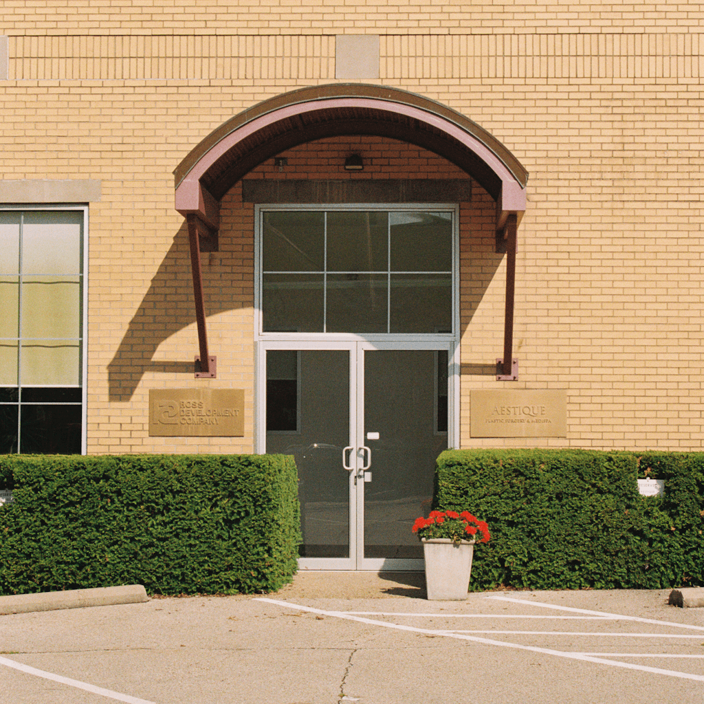 The scene is set outdoors in front of a building with a light yellow brick façade.