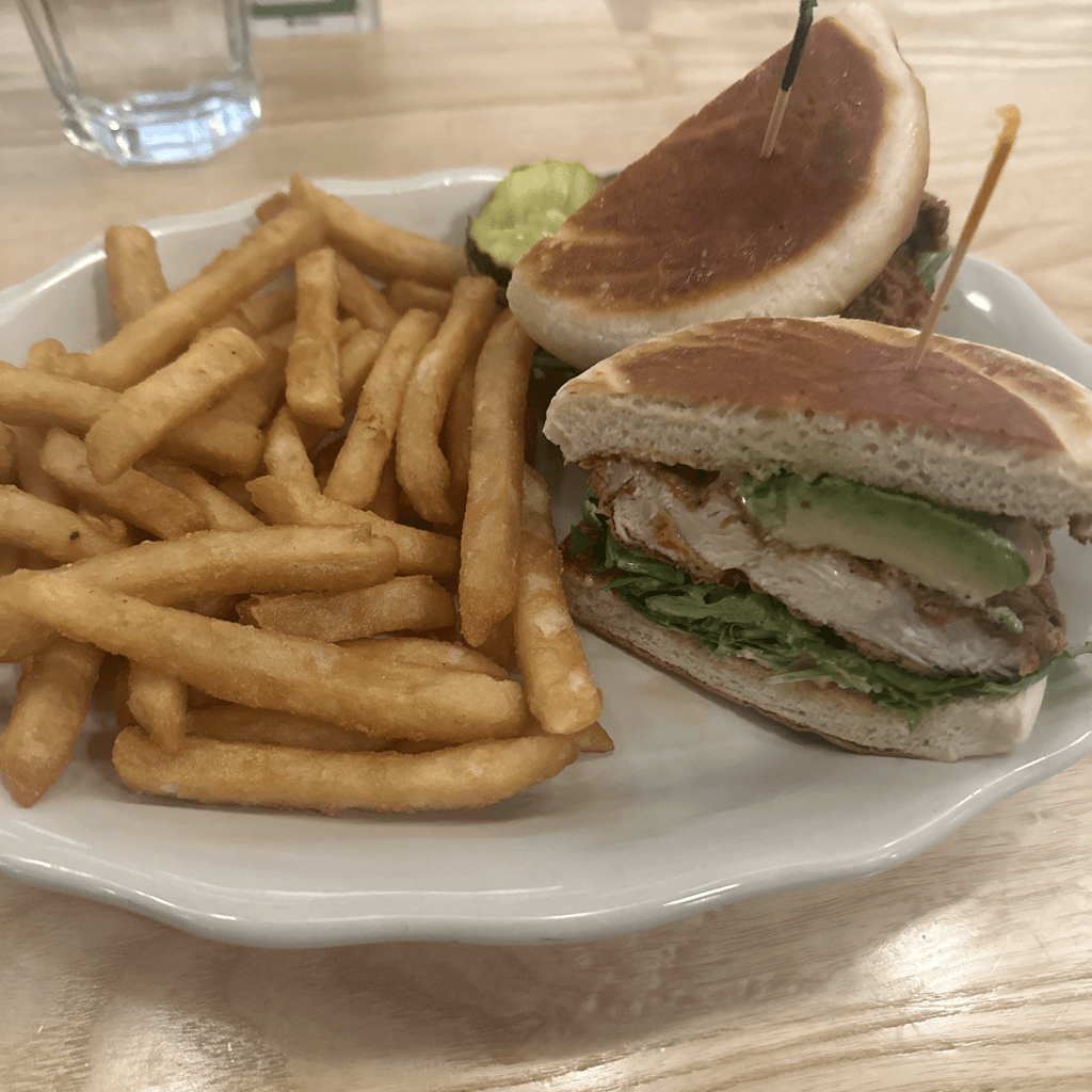 A meal is served on a white scalloped-edge ceramic plate resting on a light wood-grain table, viewed from a close, slightly elevated angle.