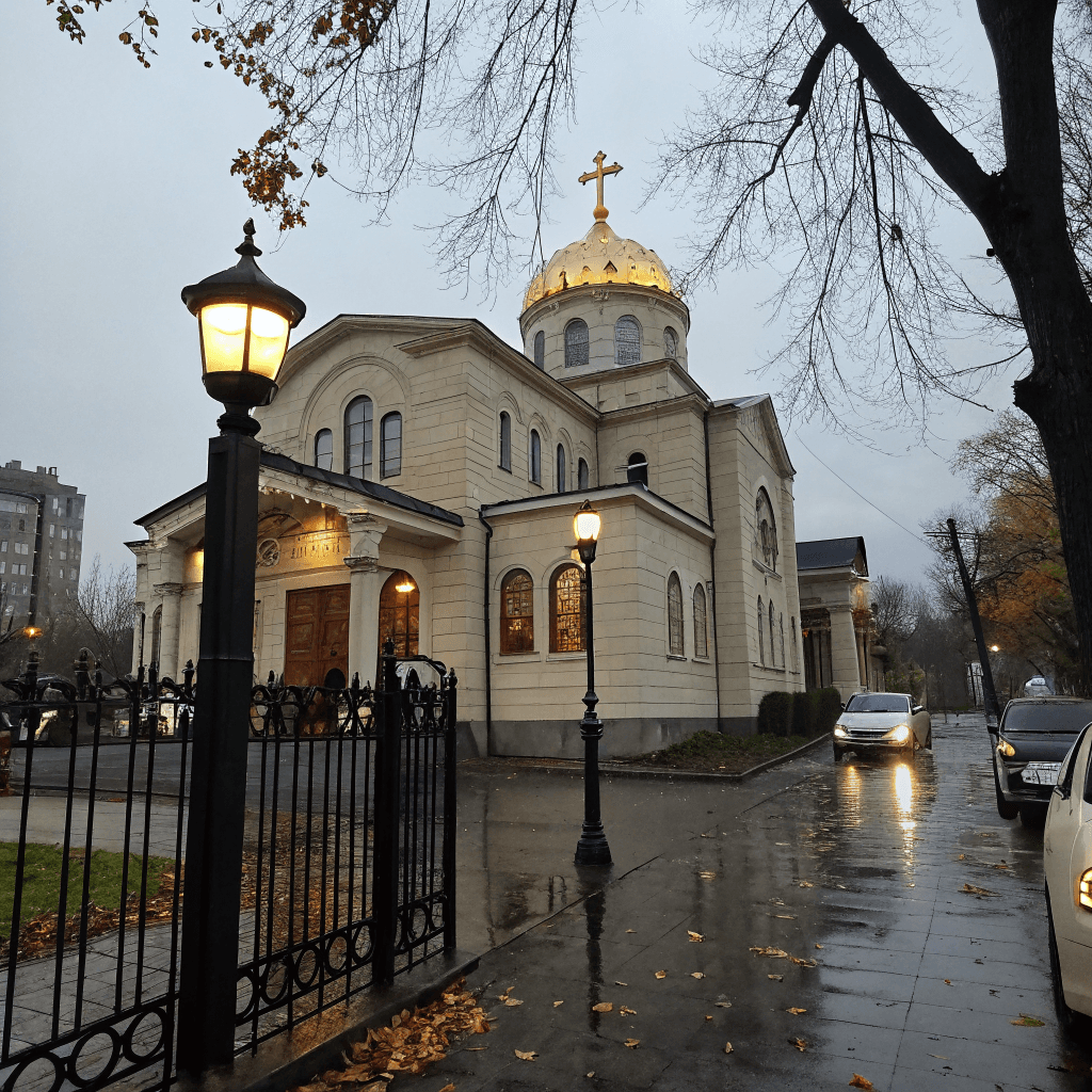 An Orthodox cathedral with a prominent golden dome topped by a cross rises in the midground, its pale stone facade banded in horizontal courses, featuring arched windows, rounded apses, and a grand arcaded entrance porch with columns.