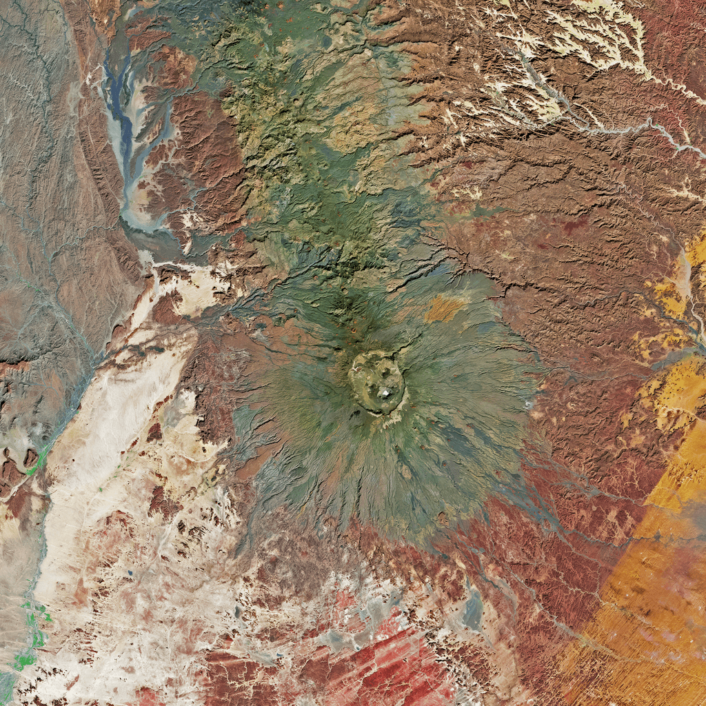 The scene is an expansive aerial view of a vibrant and varied landscape, likely viewed from high above the earth.