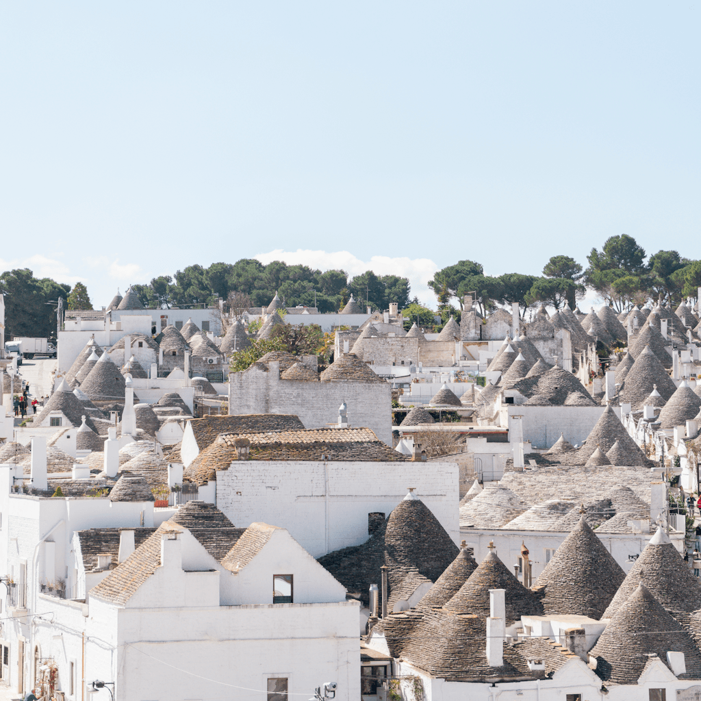 The scene captures an outdoor view of a quaint village during the daytime, under a clear, bright blue sky.