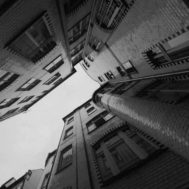 The scene is set outdoors, in an enclosed courtyard surrounded by tall, multi-story brick buildings.