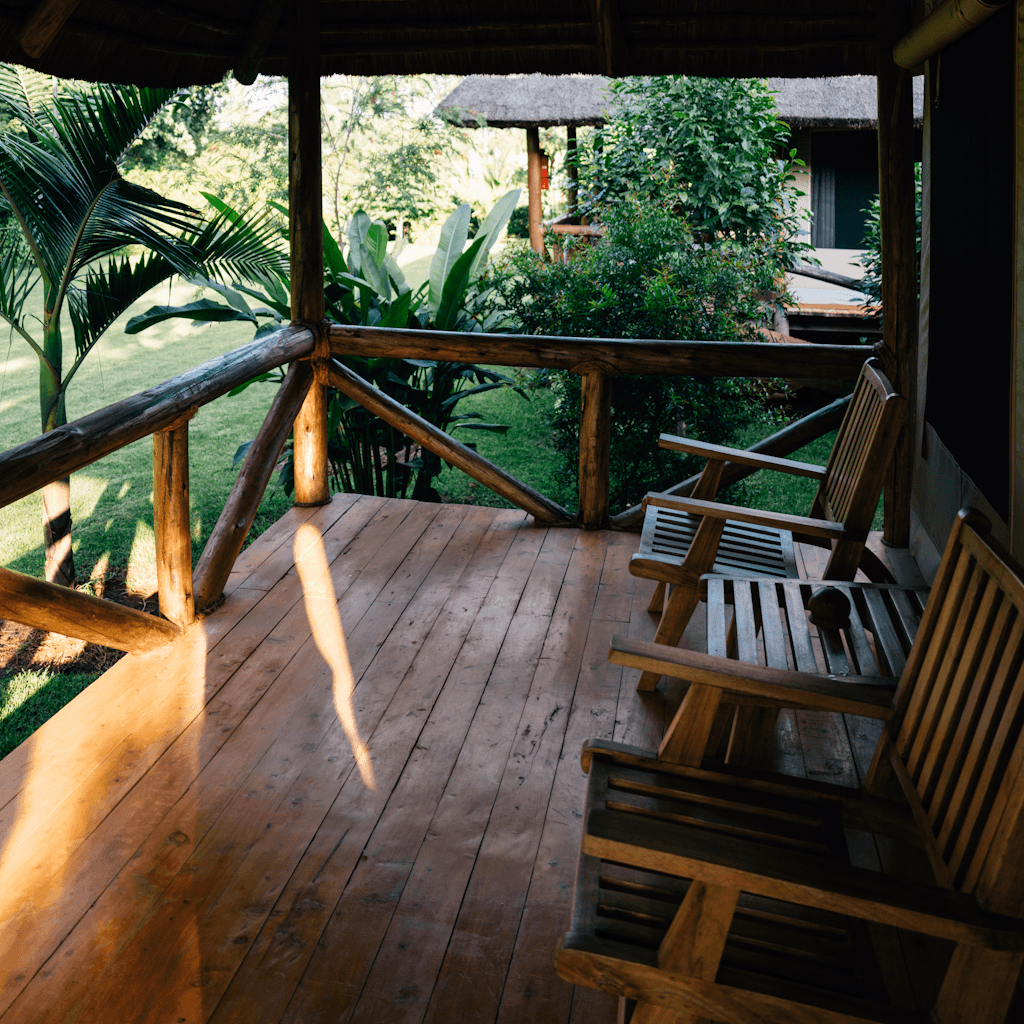 The scene is set on a rustic, wooden veranda in a lush, tropical outdoor setting.