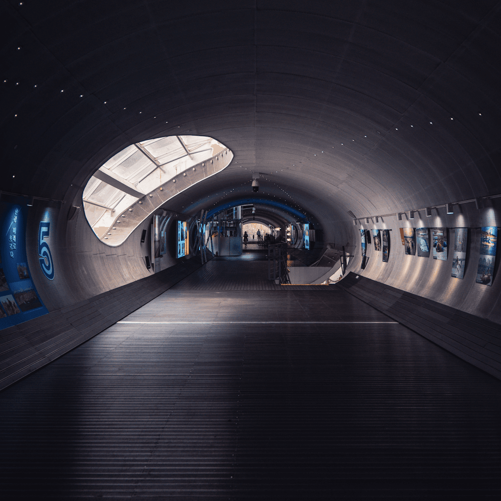 The scene is set in a sleek, modern indoor passageway with a tunnel-like architecture.